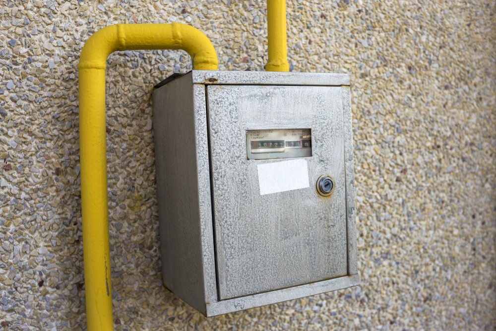 Gas meter inside a metalic box with gas lines coming out of it.