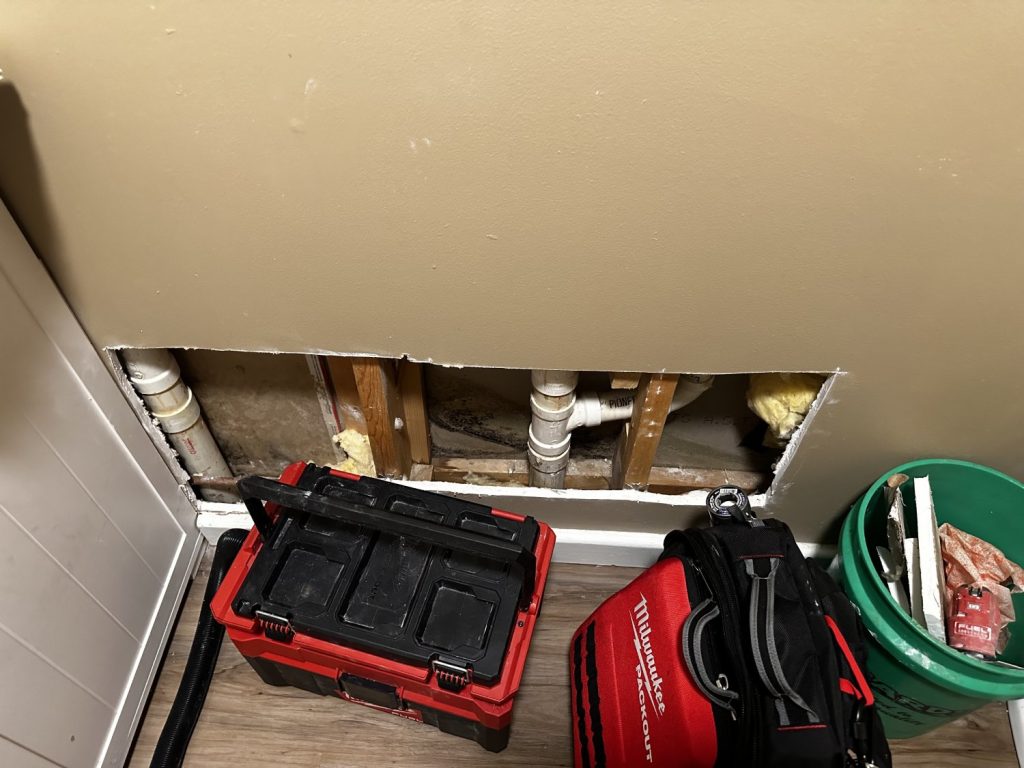 Wall opening revealing a pipe leak repair