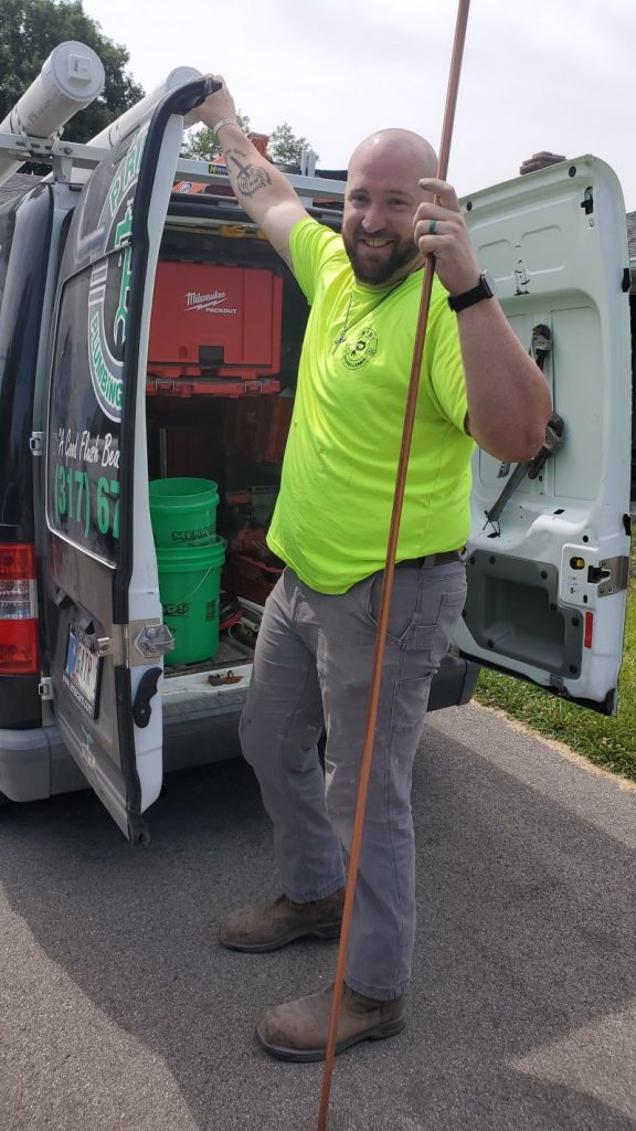 Plumber holding copper pipe next to work van