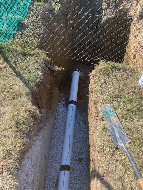 Sump pump discharge line installation in outdoor trench