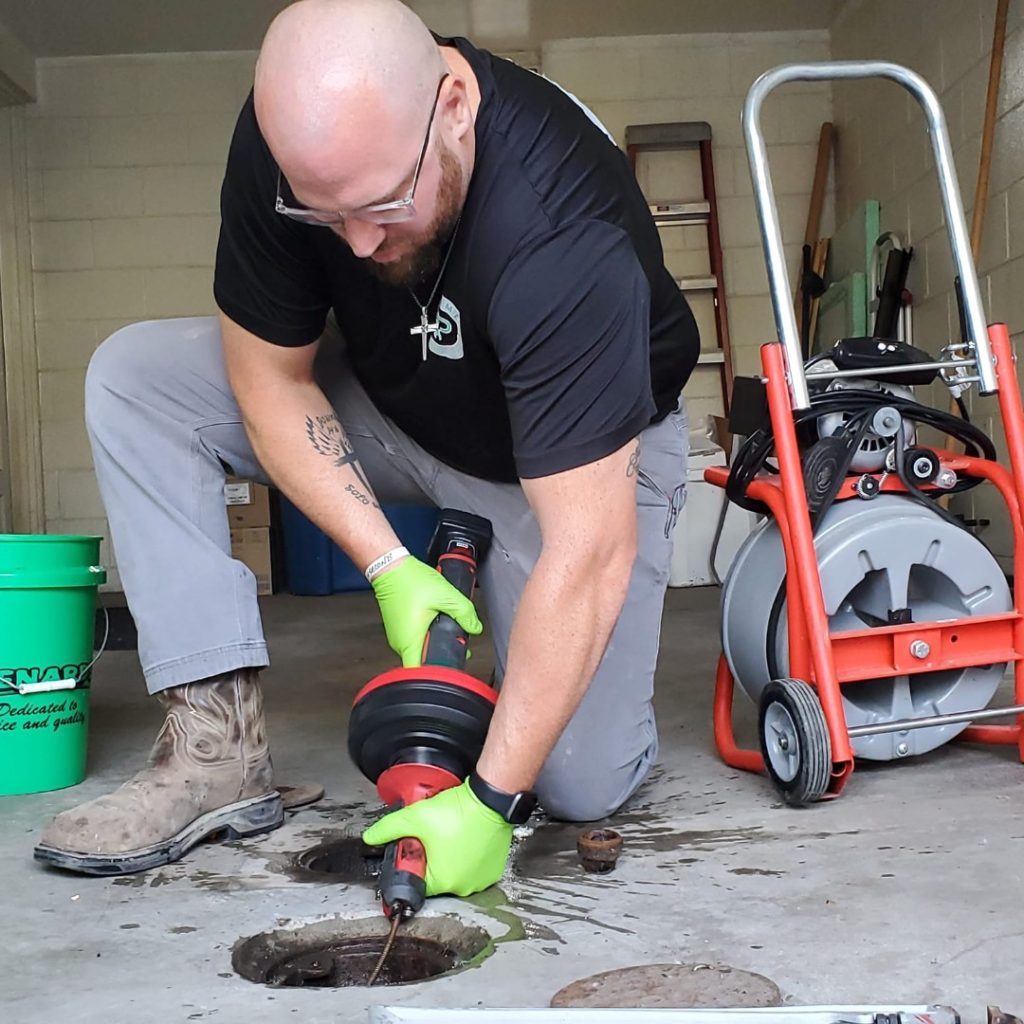 Plumber cleaning a drain with a drain auger