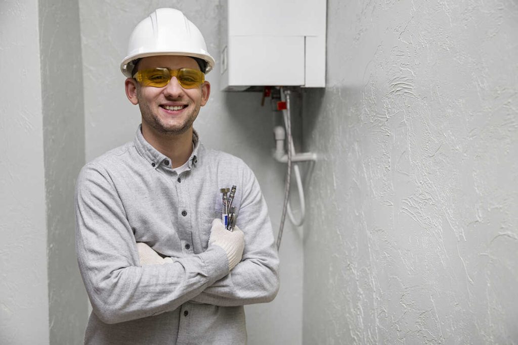 Plumbing expert standing beside a newly installed tankless water heater unit.