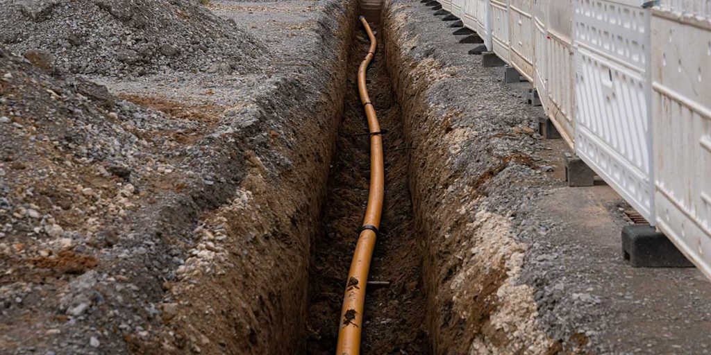 An exposed underground pipe with fittings surrounded by soil, illustrating vulnerability to shifting ground and soil movement.