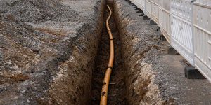 An exposed underground pipe with fittings surrounded by soil, illustrating vulnerability to shifting ground and soil movement.
