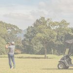 Golfer taking a swing on a scenic green course with a golf cart nearby during the annual Foundation Fest event.